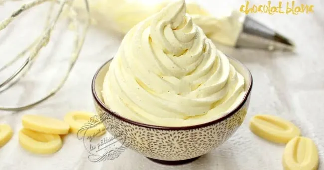 Bol contenant une ganache au chocolat blanc onctueuse, spatule recouverte de crème, tablette de chocolat blanc cassée et torchon en lin.