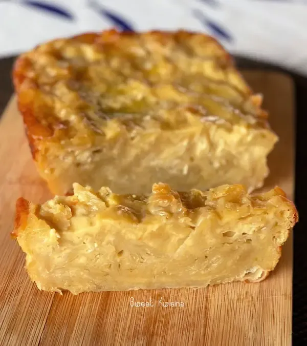 Une main soulève une feuille de pâte filo dorée, empilement de feuilles translucides sur un plan de travail en bois, torchon propre posé à côté