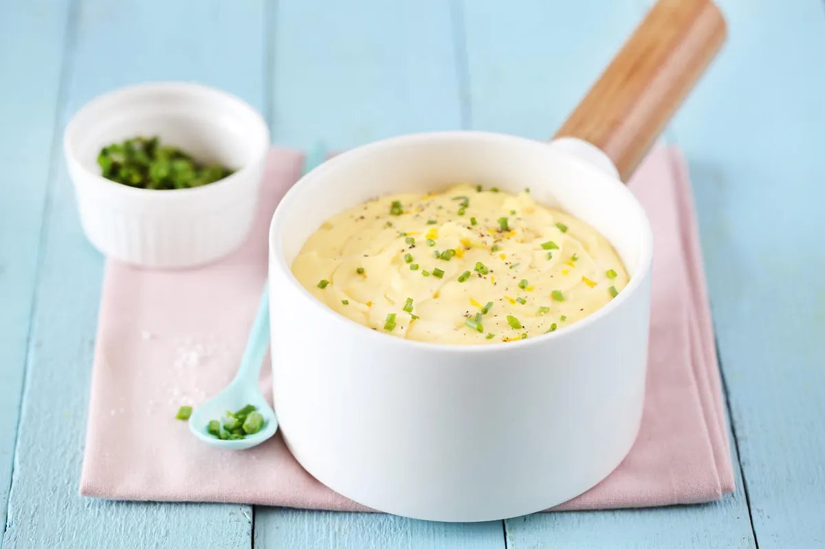Sauce au beurre citron nappant le dos d'une cuillère, brillante et jaune pâle, avec un zeste de citron jaune posé à côté